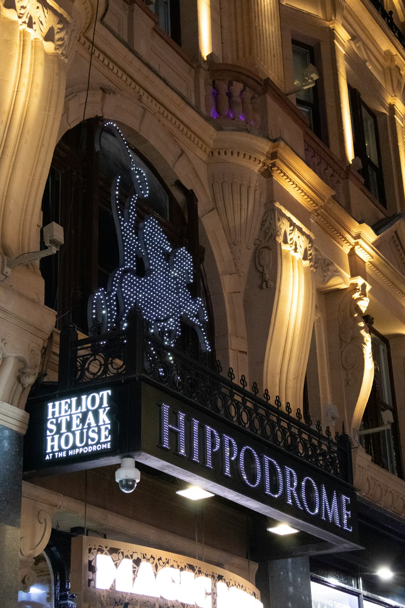 Leicester Square illuminated at night with West End theatre marquees and neon lights, London