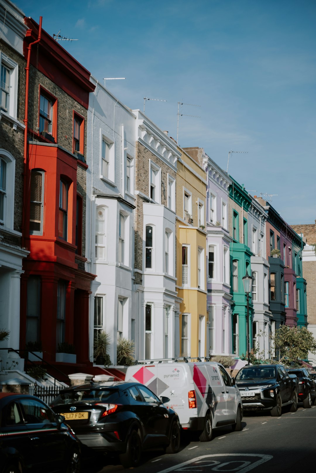 Pastel-coloured terraced houses on a Notting Hill street with flower-adorned balconies, West London