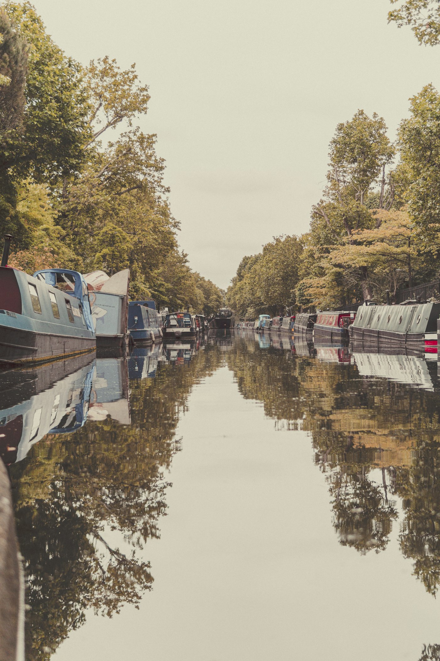 Narrow boats moored on the Grand Union Canal at Little Venice, Paddington, with tree-lined towpath